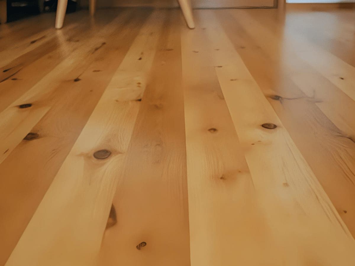 Close view of pale blond plank flooring with visible knots and tight grain